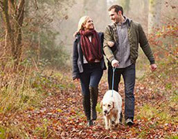 Possum Lodge Cabins - A photo of a man and woman walking a dog on a wooded path. Possum lodge is your romantic Ohio cabin getaway.