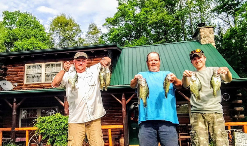Ohio Lake Region Escape - A photo of three happy fishermen in front of Possum Lodge Cabins holding the fish they caught for the day.